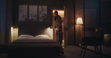 Yorgun adam geceleri rahat bir otel odasında kalıyor. Gri Saçlı Adam Çıplak Yatağa Yatar. Konsept, iş gezisi, otel hayatı, gezgin yaşam tarzı, seyahat yorgunluğu. Doli Vuruşu.