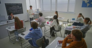 Öğrenciler ve Öğretmen Dinlemede Özenli Sunum Öğrencilerden biri. Çocuk tüm grubun önünde Kodlama Projesini savunuyor. Eğitim Geliştirme, BTMM Eğitim, sınıf tartışması. Doli Vuruşu.