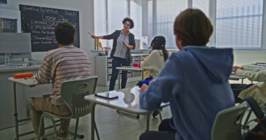 Kadın Öğretmen, Parlak Sınıftaki Öğrenci Grubu 'na Kodlama Görevini Açıklayan Tahta Yakınında Duruyor. Okul ortamında Modern Eğitim, Etkileşimli Öğrenme, Yaratıcı Takım Çalışması Konsepti.