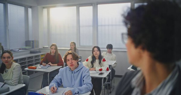 Закрывая глаза, взрослая женщина активно машет маркером на невидимой интерактивной доске. Студенты слушают внимательно. Концепция современных методов обучения, инновации в области образовательных технологий.