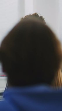 Kendinden emin kadın eğitimci, sınıf tartışmasını coşku ve empati ile yürütüyor. Yenilikçi Amerikan Öğretim Tarzı, Öğrenci Katılımı, İşbirlikçi Öğrenme Ortamı. Dikey Çekim.