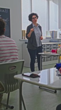 Kadın Öğretmen, Parlak Sınıftaki Öğrenci Grubu 'na Kodlama Görevini Açıklayan Tahta Yakınında Duruyor. Modern eğitim kavramı, etkileşimli öğrenme, yaratıcı takım çalışması. Dikey Çekim.