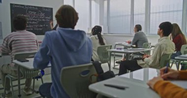 Kendine Güvenen Bayan Öğretmen Öğrencilere Kodlama Görevlerini Açıklıyor. Gençler dikkatle dinler, notlar alır ve fikirleri tartışırlar. Modern BTMM Eğitim, Takım Çalışması, Yenilikçi Öğrenme Ortamı. Doli Vuruşu.