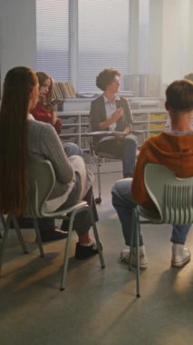 Genç öğrenciler, İlgili Öğretmenler ile Çemberde oturup Psikoloji ve Öz-Farkındalık 'ı tartışıyorlar. Modern Okullarda Öğrenci Refahı, Farkındalık ve Duygusal Desteğin Önemi. Dikey Çekim.