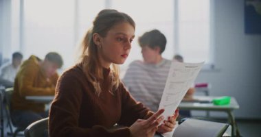 Genç Bayan Öğrenci Sınav Raporu Olarak Parlak Gülümsüyor ya da Parlak Sınıfta Masada Otururken Başarılı Sınav Kağıdı. Akademik Başarı Kavramları, Öğrenci Başarı, Öğrenim Keyfi.