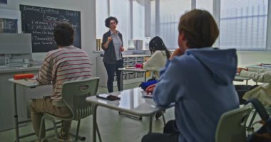 Kadın Öğretmen, Parlak Sınıftaki Öğrenci Grubu 'na Kodlama Görevini Açıklayan Tahta Yakınında Duruyor. Okul ortamında Modern Eğitim, Etkileşimli Öğrenme, Yaratıcı Takım Çalışması Konsepti.