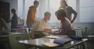 Gençler Sınıf Masası 'nda Oyuncak Parmak Güreşinde Güreşiyor, Akranlar izlerken Gülüyor ve Rekabet Ediyor. Takım çalışması, erkeklik, arkadaşlık ve pozitif öğrenci dinamiği kavramı..