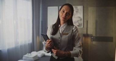 Gülümseyen Genç Kadın Otel Hizmet Görevlisi Üniformalı Tablet, Modern Lüks Otel Odasında Güvenle Duruyor. Konukseverlik Yönetimi ve Üst Düzey Müşteri Hizmetleri. Portre.