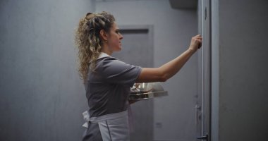 Gri üniformalı, Dost canlısı Bayan Otel Görevlisi Oda Servisi 'nden. Gümüş Kubbe şekilli süslemeli tepsi taşıyan bir kadın. Premium Catering ve Lüks Konukseverlik. Doli Vuruşu.