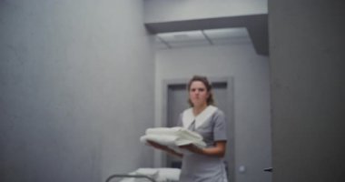 Kıvırcık saçlı otel temizlikçisi misafir odasının kapısını açar ve servis arabasının temiz havlularını içeri yerleştirir. Konukseverlik Standartları, Temizlik, Yeni Gelenler için Konforlu Ortam Oluşturuluyor.