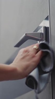 Nazikçe Kapan, Kusursuz Temizlik. Otel temizlikçisi dikkatlice kapı yüzeyini siler, kapı tutacağı, yumuşak bez ve temizleme spreyiyle kilitler. Konsept Hijyen, Konukseverlik Standartları, Misafir Odası Hazırlığı