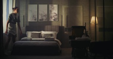 Bayan otel çalışanı karanlık süit dinlenme odasına girdi, Konuklara Konukseverlik ve İlgi Aranıyor. Yeni Havlular Yeni Misafir için Yatakta Görülebilir. Konsept Konukseverlik ve Kapatma Servisini Kabul Et.