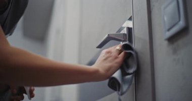 Nazikçe Kapan, Kusursuz Temizlik. Otel temizlikçisi dikkatlice kapı yüzeyini siler, kapı tutacağı, yumuşak bez ve temizleme spreyiyle kilitler. Konsept Hijyen, Konukseverlik Standartları, Misafir Odası Hazırlığı.