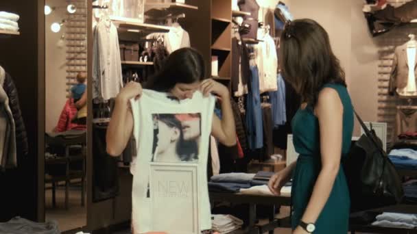 La muchacha se prueba la camiseta en la tienda — Vídeos de Stock