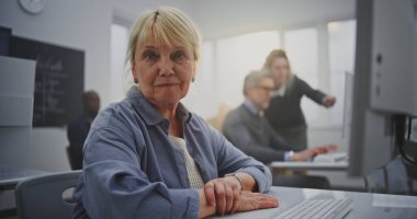 Uzun sarı saçlı, kendine güvenen yaşlı kadın. Parlak bilgisayar laboratuvarında kodlama yapıyor. Konsept Yaşlanma, Dijital Eklenti ve Kıdemli Öğrenciler İçin Teknoloji 'de Profesyonel Geri Çekilme. Portre.