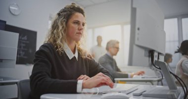 Kıvırcık saçlı kadın kodlama atölyesine katılıyor, ekrana bakıyor, içten gülümsüyor. Modern Sınıfta Yaratıcı Öğrenme, Pozitif Eğitim Atmosferi, Kum Dijital Güçlendirme. Portre.