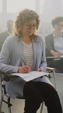 Farklı Çağlardan Grup Erkekleri ve Kadınları Sınıfın Etkinliğine Katılıyor. Odaklanmış Yetişkin Öğrenciler Öğretmenler Konferansı sırasında Notlar Yazar. Meslek Eğitimi kavramı, Ömür boyu öğrenme. Dikey Çekim.