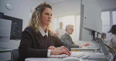 Kıvırcık saçlı kadın kodlama atölyesine katılıyor, ekrana bakıyor, içten gülümsüyor. Modern Sınıfta Yaratıcı Öğrenme, Pozitif Eğitim Atmosferi, Kum Dijital Güçlendirme. Portre.