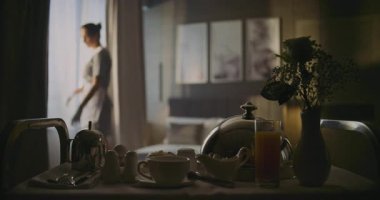 Profesyonel Otel Hizmetçisi Pencerelerde Perde Açar ve Zarif Oda 'da Temiz, Temiz Yatak Yapar. Ön plan oda servisi tramvayı ile kahvaltı. Konfor, Temizlik ve Yüksek Kalite Otel Servisi.