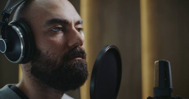 Yetenekli Ses Performansı Kayıt Merkezini Kapat. Stüdyo Kulaklığı Giyen, Yüz İfadesi ve Sesli Teslimat yoluyla Güçlü Duygular Taşıyan, Karakter Yorumlama Sanatı.