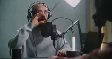 Çay ya da fincan sıcak kahveyle podcast sohbeti. Modern Stüdyo 'da İki Erkek Kaydı Podcast, Laptop, Mikrofonlar ve İçkiler ile Masa Arasında Konuşma. Erkekler Kontrast Hareketleri Anahtar Noktaları Vurguladı.