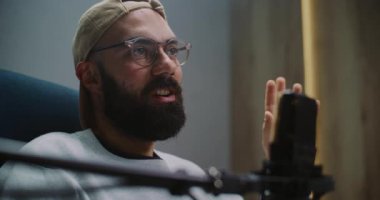 Modern Ses Stüdyosunda Kendinden emin Sakallı Sunucu Animasyon Hareketleriyle Kaptan Konuşmaları Giyiyor. Yüksek Kalite Mikrofonla Erkek Etkileşimi. Otantik İletişim ve Hikaye Anlatımı kavramı.