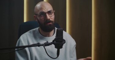 Modern Profesyonel Ses Stüdyosunda Gözlüklü Erkek Podcaster ya da Uzman Sözcü Profesyonel Mikrofona Konuşuyor. Dijital Seyirciyle Doğrudan İletişim, Müdahale. Portre.