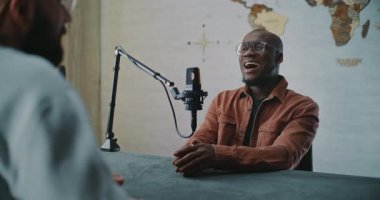 Rahatlamış Stüdyo Konuşması sırasında Gülümseyen Podcast Misafir Paylaşım Sezgileri. Afrikalı Amerikalı Adam, Stüdyo Konuşması sırasında Sezgileri Paylaşırken Gülümsüyor, Kayıt Ortamı Sorularına Yanıt Veriyor.