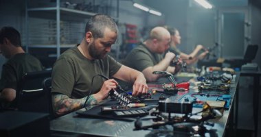 Erkekler ve kadınlar da dahil olmak üzere çeşitli uzmanlar yüksek teknoloji atölyesinde lehimleme ve bilgisayar tasarımı gibi çeşitli görevler yaparlar. Drone Geliştirmede Uzman Roller ve Cinsiyet Çeşitliliği kavramı.