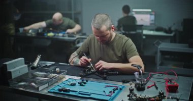 FPV İHA devrelerinde teknisyen lehimleme bileşenleri. Küçük Elektronik Bileşenleri İHA 'nın bir parçası olan küçük devre panosuna dikkatlice lehimleyen adam. Modern Atölyede Hassas Elektronik Kurulum.
