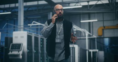 Bilgi İşlem Müdürü cep telefonundan çağrıya cevap veriyor. Odaklanmış Bilişim Yöneticisi, Veri Merkezi Sunucu Salonundaki Acil Cep Telefonu Görüşmelerine Yanıt Verdi. Hızlı İletişim, Bilişim Krizi Yönetimi ve Sorumluluk kavramı.