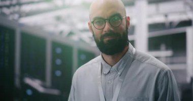 Modern Sunucu Altyapısını Denetleyen Odaklanmış Bilgi İşlem Yöneticisi. Sakallı Gözlüklü Erkek ve Kimlik Rozeti Denetleme Veri Merkezi 'nin Altyapısı. Teknoloji ve Profesyonel Gözetim. Portre.