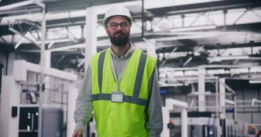 Mühendis telsiz aracılığıyla fabrikada iletişim kuruyor. Sert Şapka ve Güvenlik Yeleği 'ndeki Sakallı Mühendis Büyük Endüstriyel Alanda Telsiz Koordinat Takımları Kullanıyor. Operasyon Raporu, Proje Yönetimi.