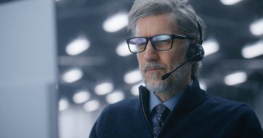 Veri Merkezi 'nde Profesyonel Kulaklıkla Konuşan Ciddi, Gri Saçlı Kıdemli Erkek Mühendisin Kapanışı. Uzaktan Teknik Destek, Müşteri İletişim ve Bulut Çözümleri kavramı. Portre.