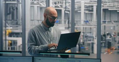 Dizüstü bilgisayarlı Mühendis İzleme Üretim Süreci. İnce dizüstü bilgisayarda deneyimli Erkek Uzman Denetleme Üretim Akımı ve Ölçümleri. Akıllı Üretimdeki Mühendislik Gözetimi, Dijital Araçlar.