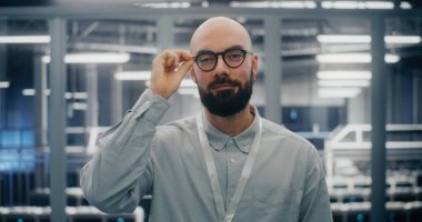 Sakallı, gözlüklü, erkek bilişim mühendisi, göz giysisini düzeltirken kendine güvenen. Yüksek Teknoloji Veri Merkezi 'nde Güvenlik Altında Adam. Konsept Uzmanlık ve Profesyonel Davranış. Portre.