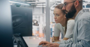 Uzmanlar Üretim Özelliklerini Tartışıyor. İki Teknik Uzman Bilgisayar Ekranında Kompleks Teknik Modelleri Derinden İnceleme Yapıyor. Kritik Sorun Çözme.