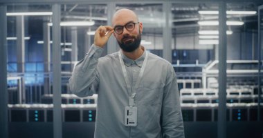 Veri Merkezi Kontrol Odası 'nın Mavi Aydınlık Ortamı ve Kum Metali Yapılarında Sıcak, Profesyonel İfade Uzmanı. Teknik Yetkinlik ve Pozitif Mesleki Tavır. Portre.