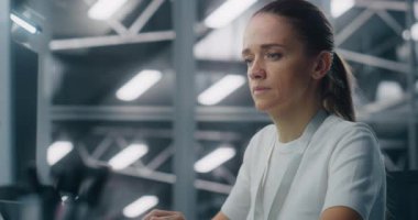 Sistem İzleme İş İstasyonuna Odaklanan Bayan Bilişim Mühendisi. Arka plan Mavi Edebiyat, Veri Merkezi Kontrol Odası Yüksek Teknoloji Ortamı. Kritik Analiz ve Profesyonel Adanmışlık.