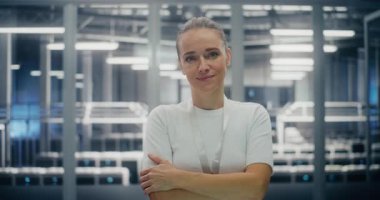Kolları çaprazlanmış gülümseyen kendinden emin kadın bilişim lideri. Modern Veri Merkezi 'nde, Güvenliğin Ortasında Duran Genç Kadın. Profesyonellik, Teknoloji Uzmanlığı ve Otorite kavramı. Portre.