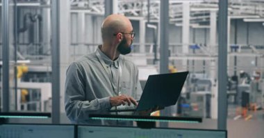 Dizüstü bilgisayarlı Mühendis İzleme Üretim Süreci. İnce dizüstü bilgisayarda deneyimli Erkek Uzman Denetleme Üretim Akımı ve Ölçümleri. Akıllı Üretimdeki Mühendislik Gözetimi, Dijital Araçlar.