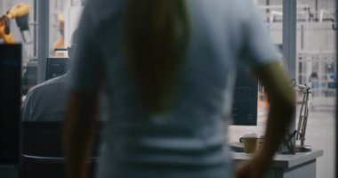 Modern Endüstriyel Kontrol Odası 'nda çalışan iki profesyonel ve Otomasyon Ölçümleri Gösteren İkili Monitörlere odaklanmış bir mühendis. Akıllı Üretimdeki Veri Analizi ve Robot Yönetimi.