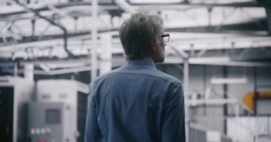 İşletme Yöneticisi Büyük Ölçekli Veri Merkezi 'ni Denetliyor. Gri Saçlı profesyonel bilişim mühendisi Büyük Girişim Sunucu Tesisleri 'nde geziniyor. Konsept Tesis Denetlemesi ve İşlem Ölçeği.