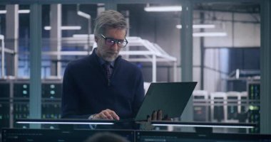 Resmi İşletme Gündelik Giyinme Stantları ve Çalışmaları Üst Yöneticisi, Laptop 'ı kullanarak Verileri Büyük Görev Kritik Sunucu Odasında Analiz Ediyor. Stratejik Analiz ve Yüksek Düzey Bilişim Yönetimi kavramı.