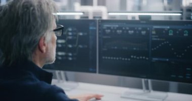 Gözlük takan, Bulut Sistemi Performans Analizi yapan Veri Bilimci Modern, Denetimli Sunucu Ortamı 'ndaki İki Büyük Ekranda Veri Akımı. Bulut Mühendisliği ve Veri Bilimi kavramı.