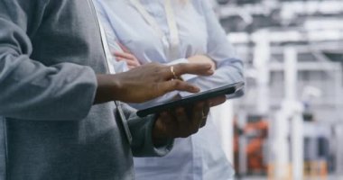 Parlak, Modern Üretim Tesisi 'nde İki Güvenlik Gözetmeninin Yakın Elleri Koordinasyon Görevi. Tablet tutan adam ve kadın jestleri. Site İletişim Verimliliği ve Güvenliğe Bağlılık.