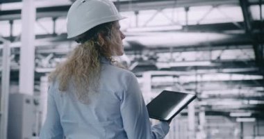 Smart Factory 'deki kompleks makineleri denetleyen kadın teknik danışman. Kadın Operasyonel Uyum ve Teknik Standartlar Uyumluluğunu Sağlama Almak İçin Mobil Aygıttan Kullanıyor. Arka Görünüm.