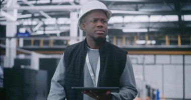 Kritik Süreç İzleme, El Bilgisayarındaki Yönetici Analiz Ölçüleri. Güvenlikli Ekipmanlı Adam Akıllı Fabrika 'da Konsantre İfadeyle Yürüyor. Gerçek zamanlı sorun çözme, Operasyonel Yoğunluk.