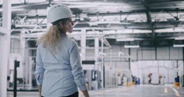 Güvenli Miğfer Uzmanı, Temiz, iyi aydınlatılmış Modern Endüstriyel Tesis. Katı Endüstriyel Kontrol, Güvenlik Protokolleri ve Yüksek Teknoloji Ortamı kavramı. Arka Görünüm.