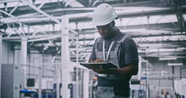 Güvenlik Başlığı Giyen Siyah Teknisyen Yüksek Teknoloji Fabrikasında Robot Silahlarla Dolu Dijital Kontrol Üretim İşlemleri Yapıyor. Endüstri Kavramı 4.0 ve Otomasyon Robot Fabrikası.